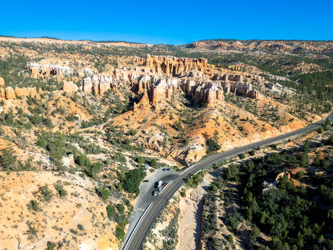 Aerial view of the rugged hoodoos and sandstone rock formations of Bryce Canyon National Park with a winding road passing through the desert landscape in Tropic, Utah, United States.