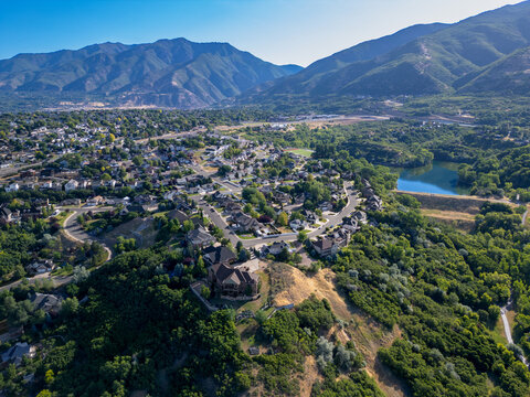 Aerial view of the Kays Creek Trail area featuring residential neighborhoods, lush green hills, and a reservoir in Layton, Utah, United States.