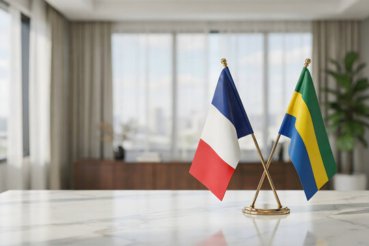 Small desk flags of france and gabon crossed on a white marble table in a blurred office interior for international diplomacy and relations