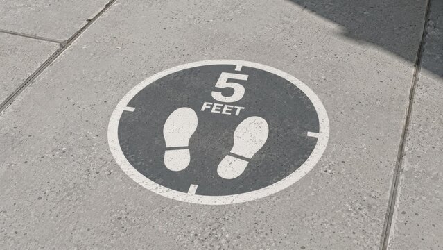 Social distancing marker on pavement indicating five feet distance for safety