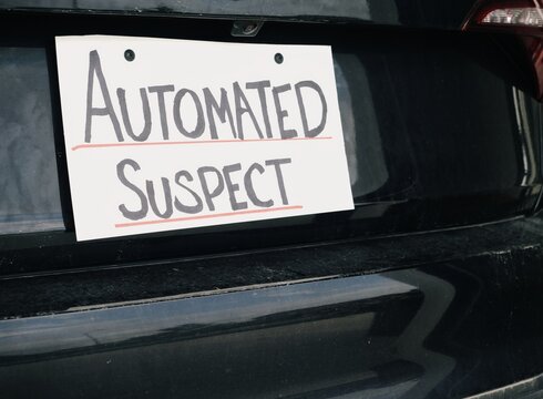 Man attaching protest license plates to vehicle using screwdriver, illustrating citizen pushback against ALPR surveillance - Fourth Amendment privacy