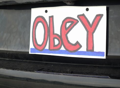 Man attaching protest license plates to vehicle using screwdriver, illustrating citizen pushback against ALPR surveillance - Fourth Amendment privacy