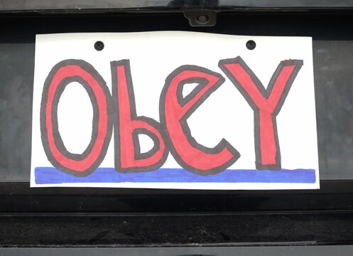 Man attaching protest license plates to vehicle using screwdriver, illustrating citizen pushback against ALPR surveillance - Fourth Amendment privacy