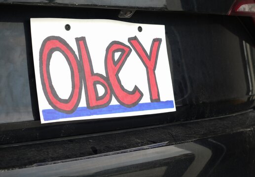 Man attaching protest license plates to vehicle using screwdriver, illustrating citizen pushback against ALPR surveillance - Fourth Amendment privacy