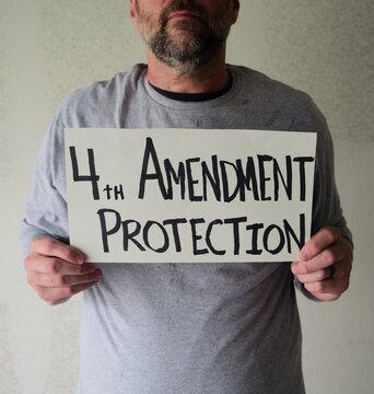 Man attaching protest license plates to vehicle using screwdriver, illustrating citizen pushback against ALPR surveillance - Fourth Amendment privacy