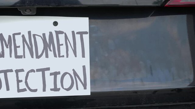 Man attaching protest license plates to vehicle using screwdriver, illustrating citizen pushback against ALPR surveillance - Fourth Amendment privacy