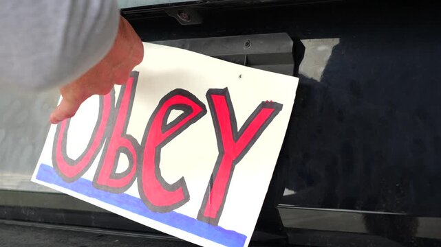 Man attaching protest license plates to vehicle using screwdriver, illustrating citizen pushback against ALPR surveillance - Fourth Amendment privacy