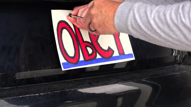 Man attaching protest license plates to vehicle using screwdriver, illustrating citizen pushback against ALPR surveillance - Fourth Amendment privacy