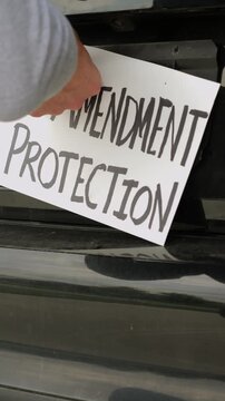 Man attaching protest license plates to vehicle using screwdriver, illustrating citizen pushback against ALPR surveillance - Fourth Amendment privacy