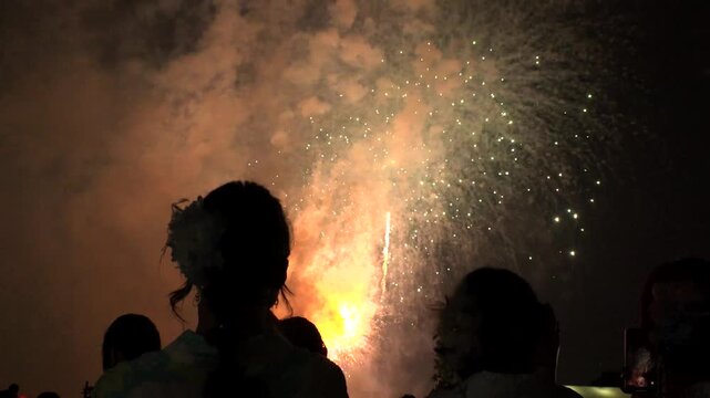 TOKYO, JAPAN - 28 JULY 2026 : Rear view of people silhouette watching fireworks show at night. Japanese romantic summer scene concept video.