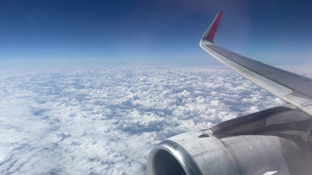 Aerial View of Airplane Wing Over Clouds