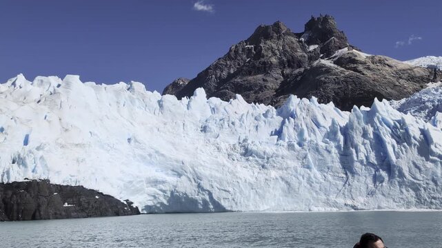 Close detailed view of the towering ice wall of Spegazzini Glacier, showing blue crevasses, jagged seracs and an overhanging section above the water of Lago Argentino.
