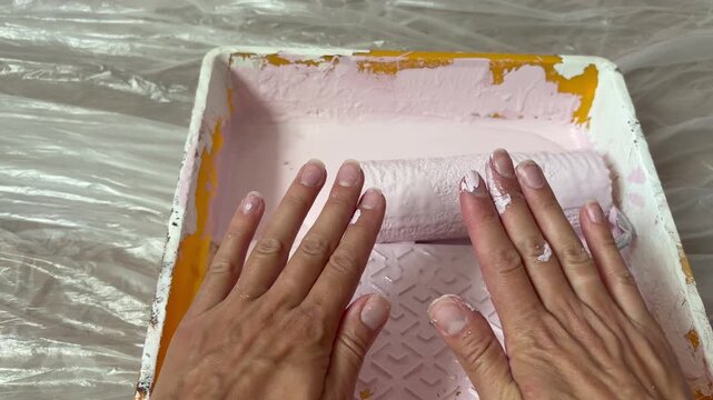 a person's hands covered in light pink paint. DIY home renovation. The person turns their hands over to show the paint on their palms and fingernails