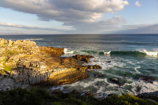 waves crashing into rocky coastline of Hermanus South Africa at sunset