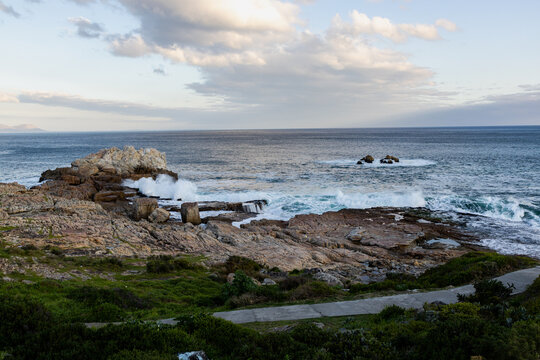 waves crashing into rocky coastline of Hermanus South Africa at sunset