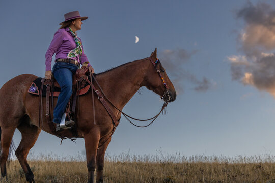 Wyoming Ranch Cowgirl with AQHA Quarter Horse moon at dusk