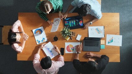 Obraz premium Top down view of businesswoman explain and present financial chart. Diverse group discuss and listening presentation about stock market statistic at meeting table with investment graph. Convocation.