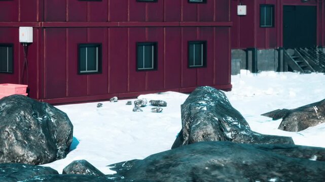 People are gathered near a red building in a snowy area. Some rocks are visible, and the scene appears cold with patches of ice. It looks like winter has fully set in.