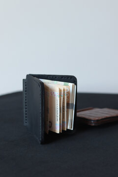 Black leather magnetic money clip wallet holding banknotes on a clean background. Minimalist handcrafted cash holder with modern design and premium everyday carry style.