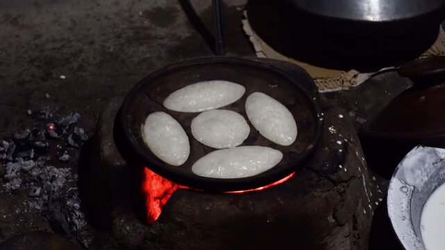 Chitai pitha is being made in a terracotta mold for making pitha in a heated clay oven. Chitai pitha is being made in a five-hole terracotta mold.