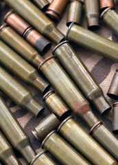 Obraz premium Big amount of shells cartridges from assault rifle bullets on old camouflage fabric