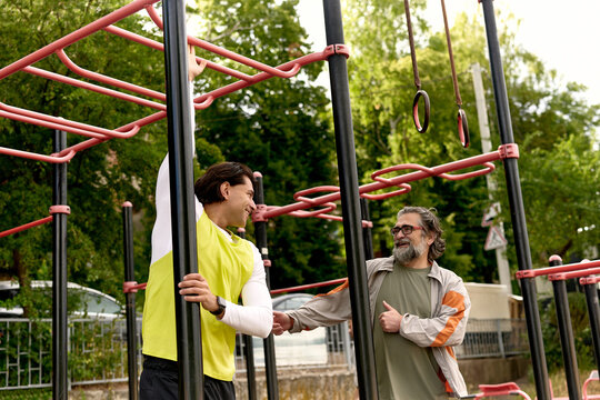 Father encouraging son on monkey bars outdoors