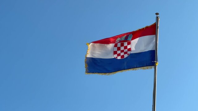 Flag of Croatia waving in the wind against a clear blue sky