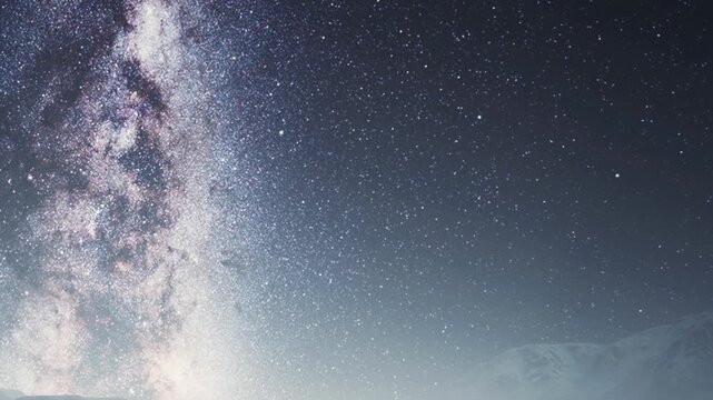A clear sky filled with stars above a mountain range. The bright galaxy is visible, creating a dramatic view during the night.