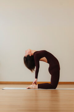 Woman practicing backbend yoga pose on mat, photographic style, warm studio background, flexibility, balance, wellness concept