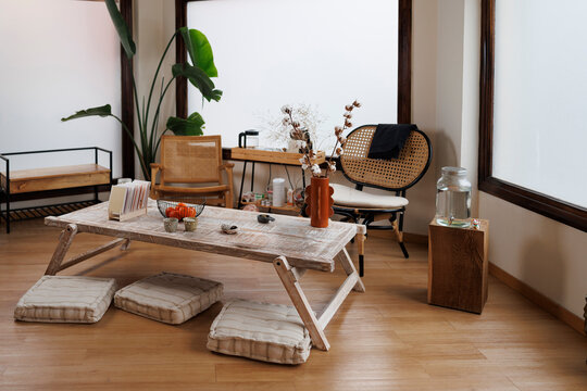 Photographic bohemian living room with furniture, woven chairs, indoor plants, and floor cushions on wood flooring, cozy home