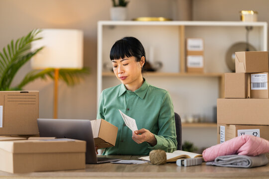 Woman running small business from home packing online orders and managing e-commerce shipments