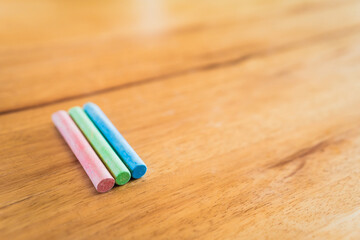 Fototapeta premium Creative educational design concept: colored pencils and chalk for back to school with a wooden table background