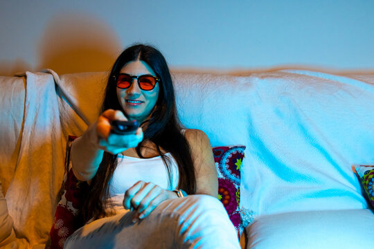 Woman watching tv at home wearing orange blue light blocking glasses