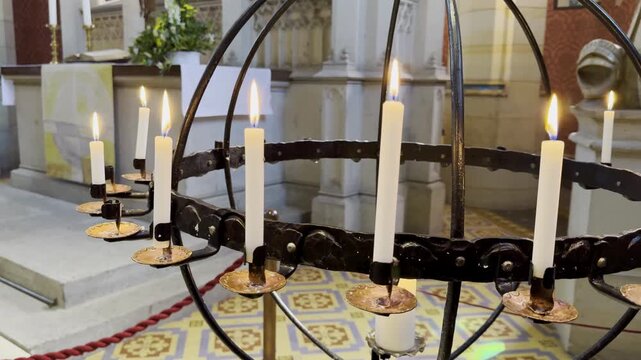 Tracking shot shows tall candles burning in ancient European cathedral