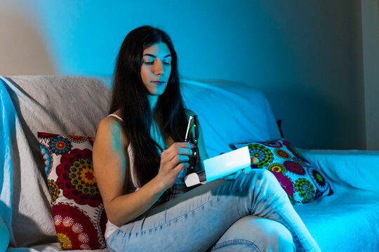 Young woman preventing blue light eye strain with protective glasses at home