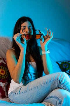 Woman wearing protective glasses with red-orange lenses, sitting at home