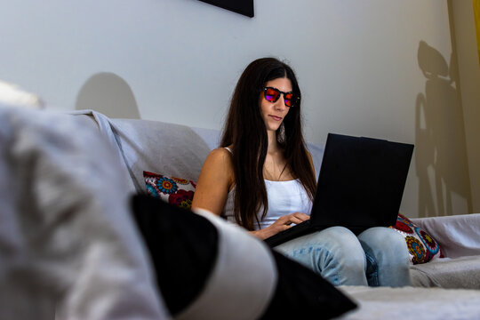Woman wearing blue light blocking glasses while working on laptop for eye protection