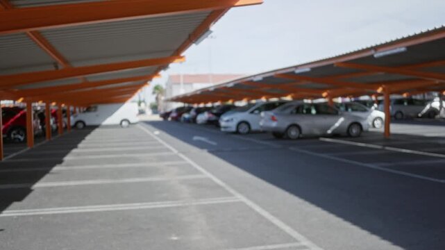 Covered parking lot under orange canopies, blurred bokeh background outdoor; background backplate copyspace calm.