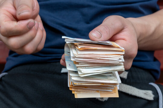 Close up of male hands counting folded Russian ruble banknotes. Man holding a stack of cash money with five hundred rubles paper currency bill on top. Financial concept of salary, savings, loan. 