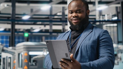 Black industry specialist examines production data in a solar technology facility, evaluating...