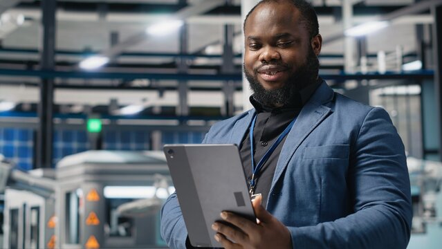 Black industry specialist examines production data in a solar technology facility, evaluating efficiency, innovation, and renewable energy operations for sustainable industrial success.