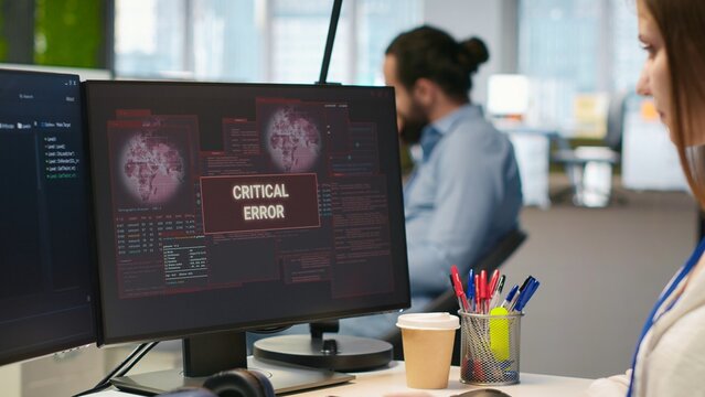Female engineer in a startup office troubleshoots a critical error warning and computer glitches while coding, performing maintenance during software development and debugging work.