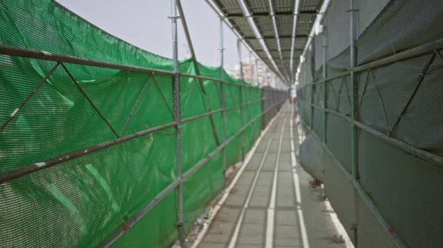 Construction scaffolding corridor with green mesh screens and shallow blurred background; background backplate copyspace calm.