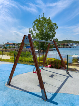 Swing set at a playground near the water in a sunny park