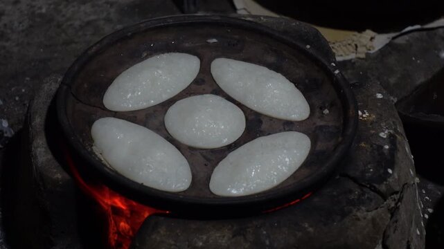 Chitai pitha is being made in a terracotta mold for making pitha in a heated clay oven. Chitai pitha is being made in a five-hole terracotta mold.
