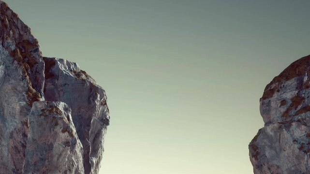 Rocks rise sharply against a clear sky with little cloud. The scene shows rugged terrain and highlights the textures of the rock formation. Sunlight illuminates the area.