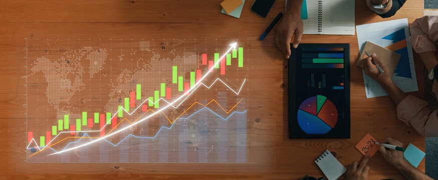Business professionals engage in financial analysis using charts and graphs on a table, showcasing teamwork and strategic planning in a modern office environment. Axiom