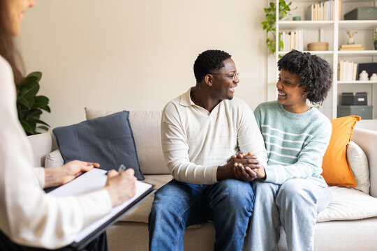 Young couple holding hands talking with psychologist on therapy session
