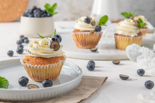Delicious vanilla cupcakes with white frosting fresh blueberries and mint