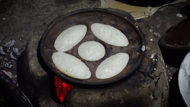 Chitai pitha is being made in a terracotta mold for making pitha in a heated clay oven. Chitai pitha is being made in a five-hole terracotta mold.